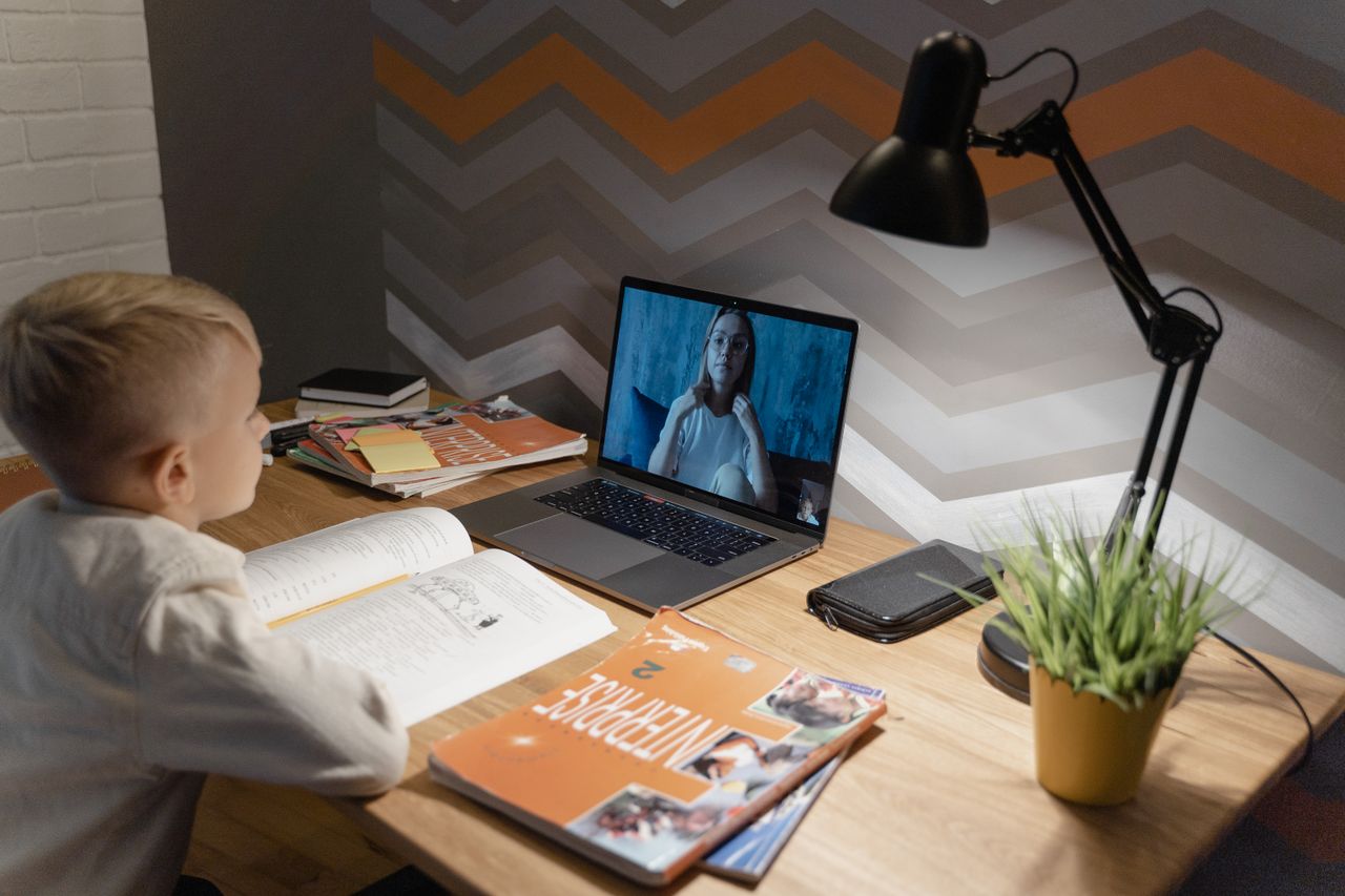 home-hero A young boy participates in a virtual class from home, using a laptop and study materials.