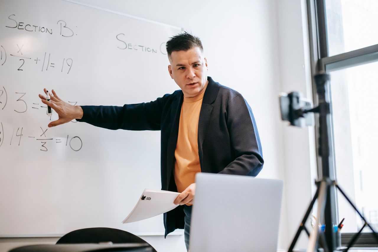 about-us Professional instructor teaching math concepts online with a laptop and whiteboard.